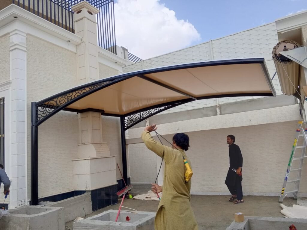عاملان يقومان بتركيب مظلة لسياره شكل مقوس في مدينة جدة حي الشاطئ